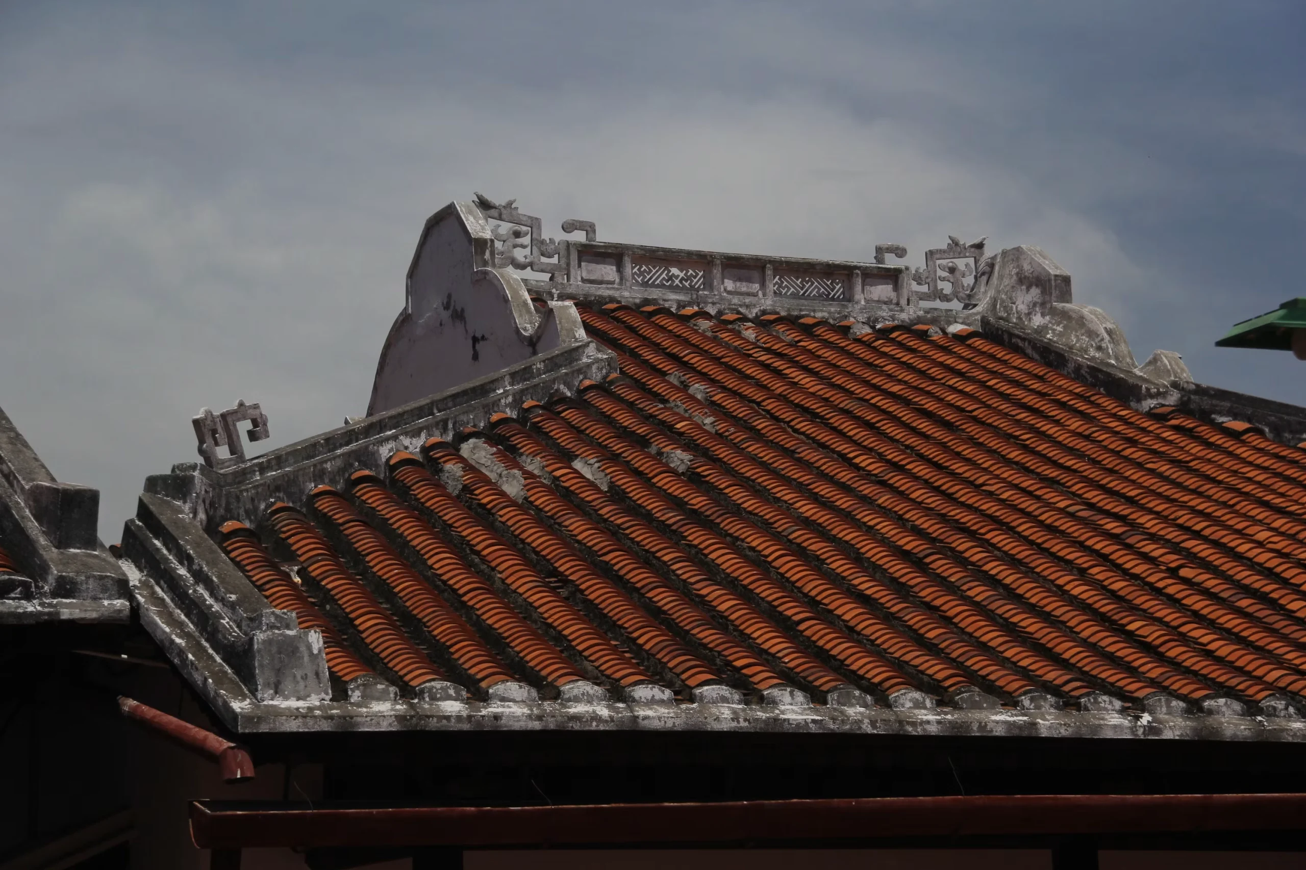 Telhado de telha tradicional com detalhes ornamentados contra o céu
